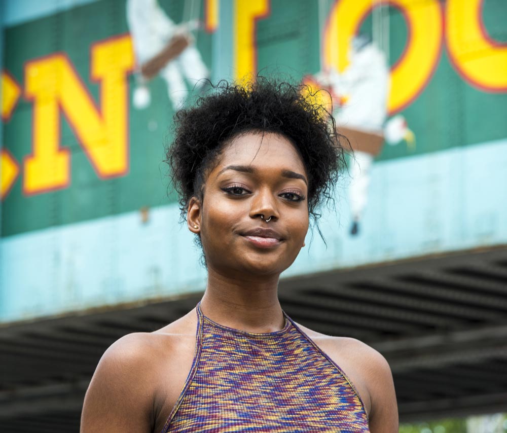 Close up Street's portraits of young woman looking in the camera at Camden Lock market, London, U.K. The sign of Camden Lock is in the background